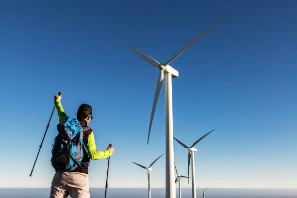 male backpacker celebrating success on hill with windmills - image alternative energy canary islands color image imagens e fotografias de stock