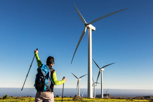 istock Traveling man with raised hand in field with windmills 1304009477