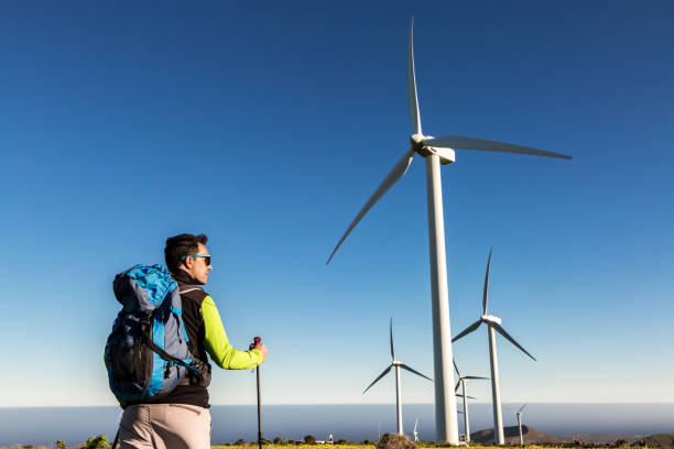 istock Male backpacker standing in field with windmills 1304009496