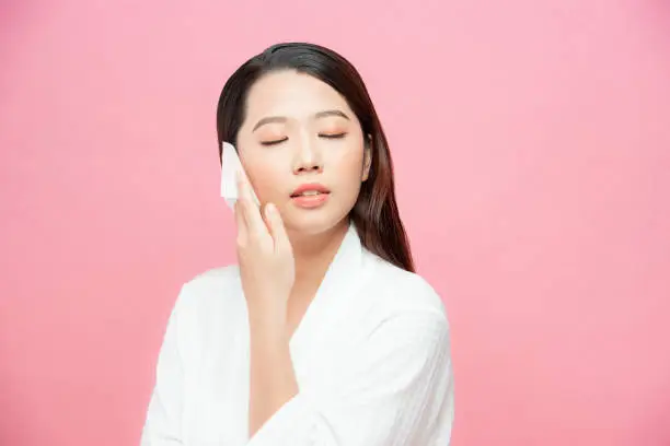 Face skin care. Smiling woman using facial oil blotting paper portrait.