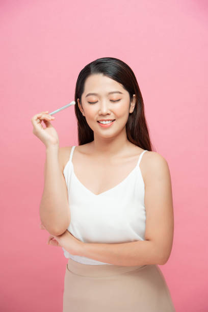 istock Young pretty brunette lady making make up with brush for eyes isolated over pink 1304010576