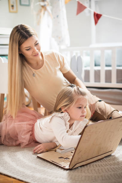 istock Mother and daughter in bedroom. Using laptop. 1304010891