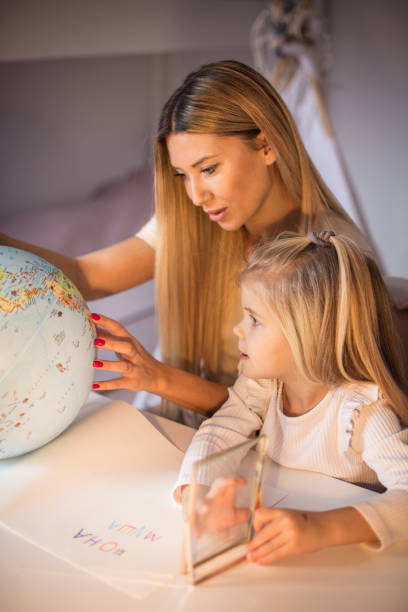 istock Mother and daughter learning geography on a world globe. 1304011267