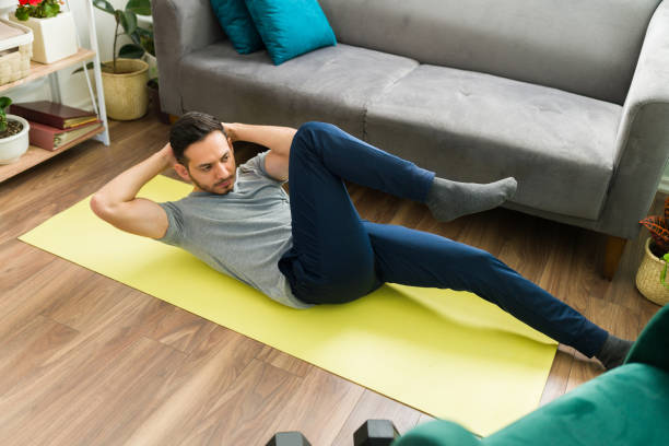 Adult man training with a high intensity interval workout Handsome man working out and doing bicycle crunches exercises in the floor of his living room. Young man starting a cardio routine sit ups stock pictures, royalty-free photos & images