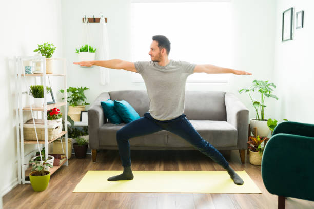 istock Hispanic man practicing a warrior 2 yoga pose at home 1304012637