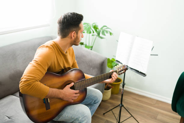 istock Hispanic guy learning how to play the guitar at home 1304013953