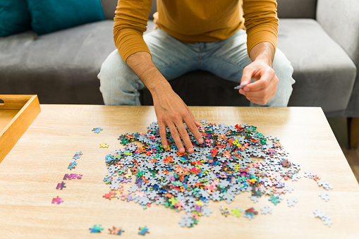 Adult man putting together a big puzzle alone