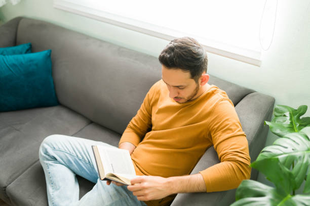 istock Handsome man enjoying a book on the couch 1304014332