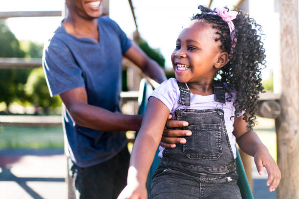 istock Close up father holding little girl going down slide 1304015295