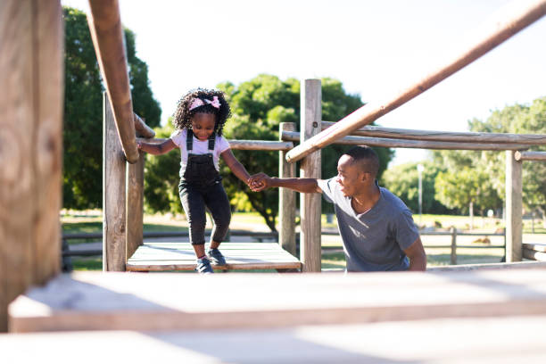 istock Father holding daughters hand on jungle gym in park 1304015343