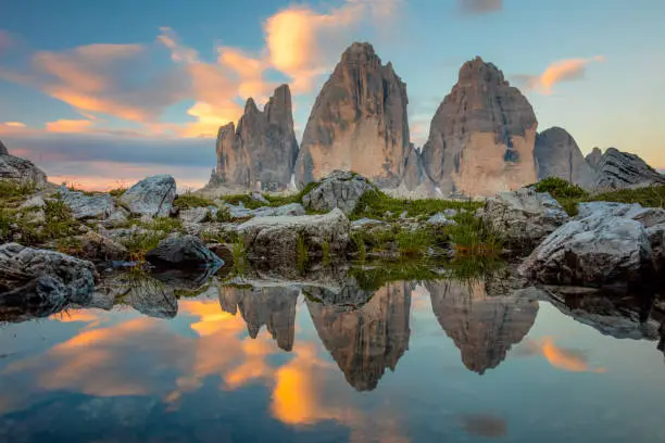 Famous Tre Cime di Lavaredo at beautiful sunrise with reflection in small lake. Landscape of Alps Mountains. One shot.  Dolomites, Alps, Italy, Europe (Drei Zinnen)