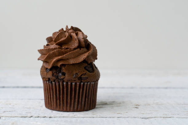 istock chocolate cupcake with whipped chocolate cream. decorated with ochocolate drops. Rustic wood background 1304015755
