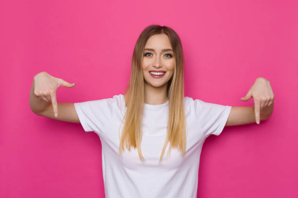 istock Casual Young Woman Is Pointing Down And Smiling 1304018059