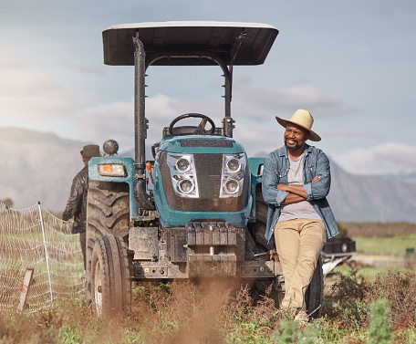 Shot of a mature man standing next to his tractor on a farm