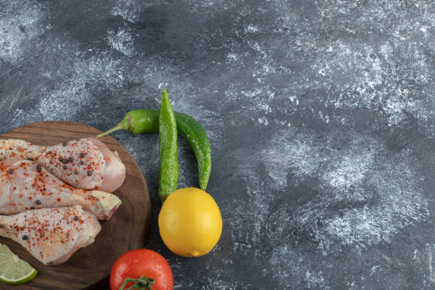 istock Fresh raw chicken drumsticks with vegetables on grey background 1304021333