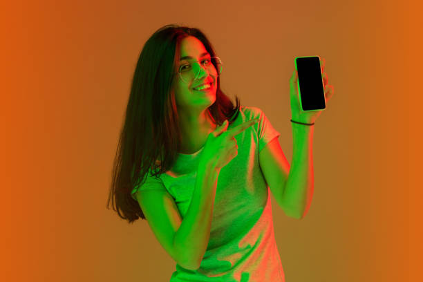 istock Beautiful girl with mobile phone isolated on studio background in neon light. 1304021670