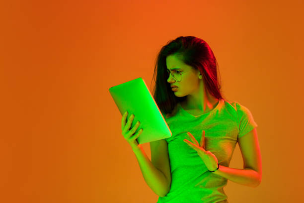 istock Beautiful girl with digital tablet isolated on studio background in neon light. 1304021678