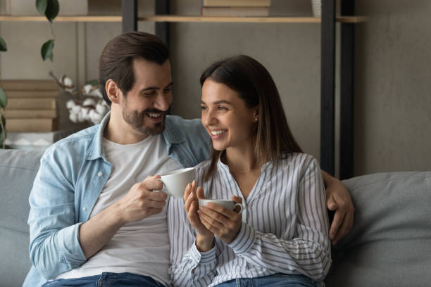 istock Smiling young couple in love sitting on couch drinking tea 1304021717