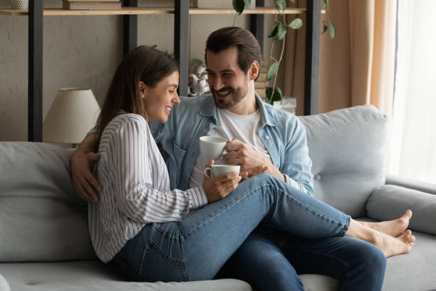 istock Affectionate young spouses cuddling on couch having pleasure drinking coffee 1304021725