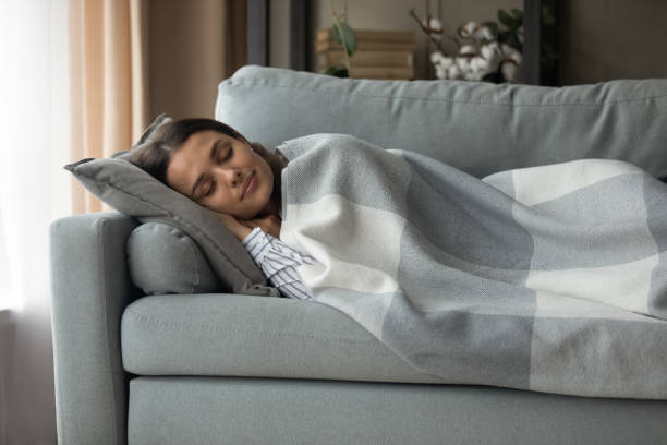 istock Serene millennial female lie on couch under blanket having sleep 1304021747