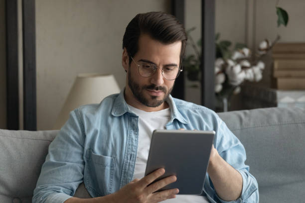 istock Serious millennial male sit on couch looking on pad screen 1304021752