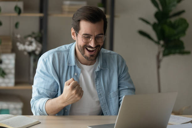 istock Happy male student sit by pc celebrate good exam result 1304021767