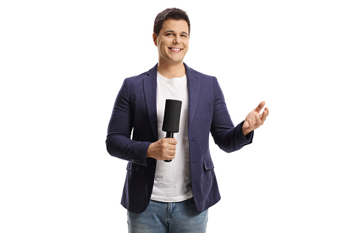 Smiling male reporter holding a microphone and gesturing wiht hand isolated on white background