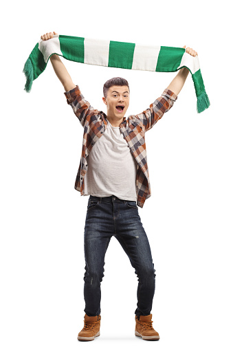 Full length portrait of an excited guy cheering with a scarf isolated on white background