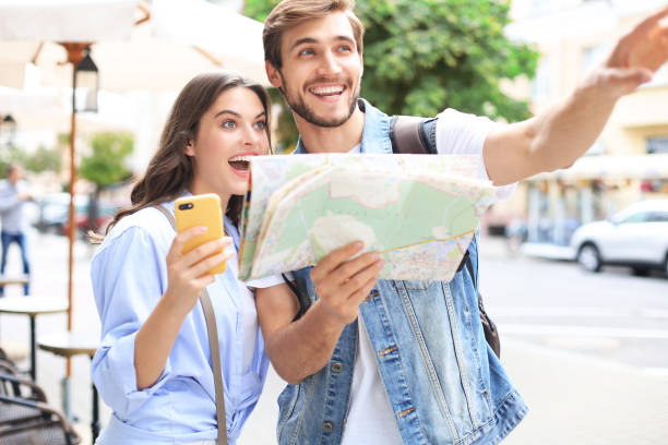 istock Beautiful young couple holding a map and smiling while standing outdoors. 1304026127