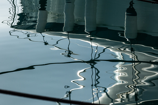 The hull of the vessel with some fenders reflects at sea.