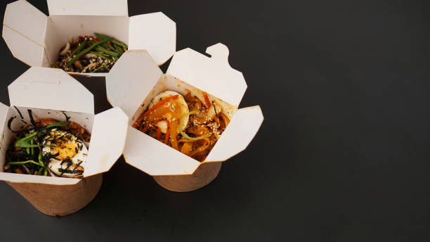istock Noodles with pork and vegetables in take-out box on black table 1304031600
