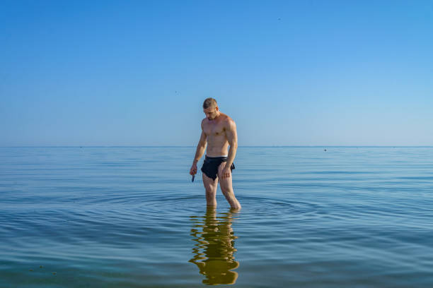 A man in a loincloth standing in water A man in a loincloth standing in water with a knife in his hand. loin cloth stock pictures, royalty-free photos & images