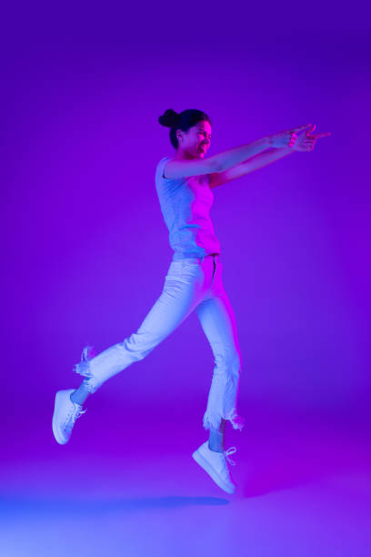 istock Young beautiful girl jumping isolated on multicolored background in neon light. 1304032772