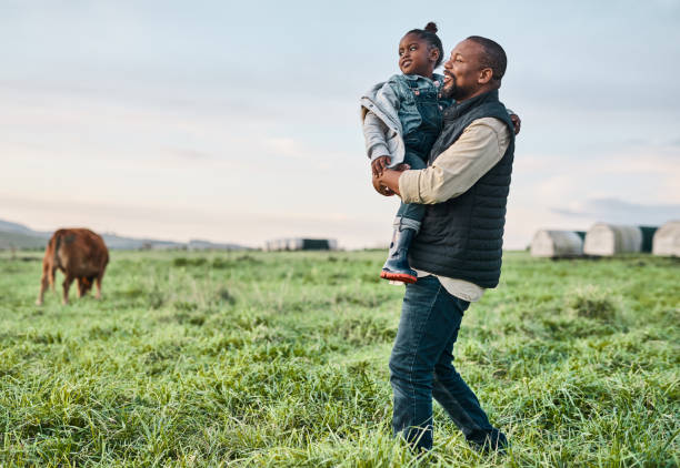 Nothing says family-friendly like an outing to the farm Shot of a mature man carrying his adorable daughter on a cow farm environmentalist photos stock pictures, royalty-free photos & images