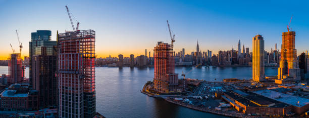 a construção de novas torres residenciais de luxo na orla de east river em greenpoint, brooklyn, e hunters point, queens, ao redor de newtown creek, com a vista panorâmica do horizonte de manhattan. panorama aéreo de alta resolução extra-grande. - manhattan aerial view brooklyn new york city - fotografias e filmes do acervo