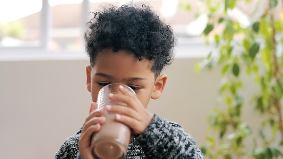 Shot of an adorable little boy having a chocolate milkshake at home