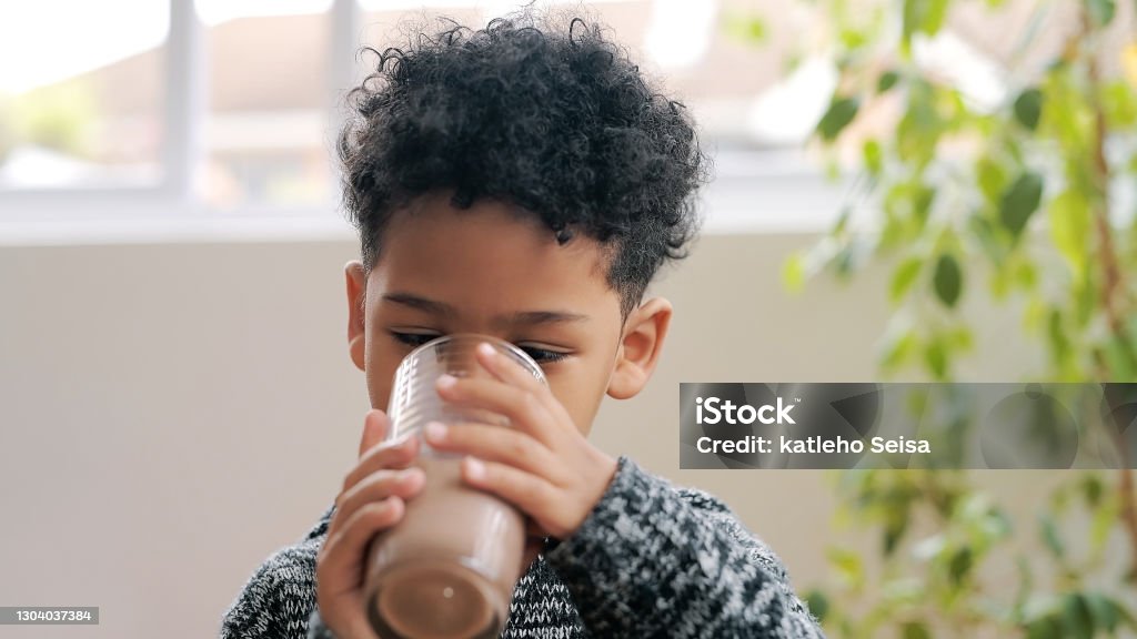 Chocolate milk, the official drink of childhood Shot of an adorable little boy having a chocolate milkshake at home Child Stock Photo