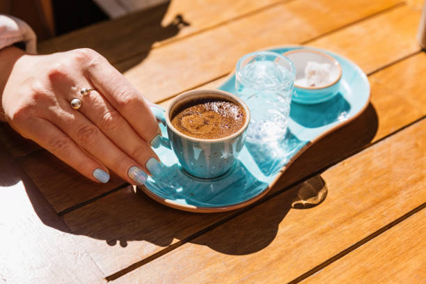 kadın elinde mavi fincanda bir fincan sıcak siyah türk kahvesi bir bardak su ve şekerle servis edilir - türk kahvesi stok fotoğraflar ve resimler