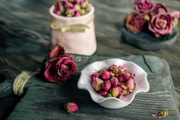 цветочные чайные розовые бутоны в белой вазе на старом деревянном столе. крупным планом - tea rose tea crop scented стоковые фото и изображения