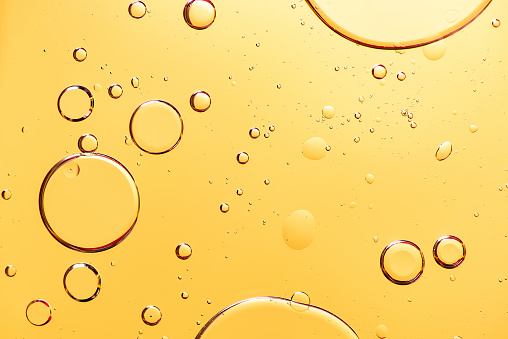 Hermosa macro foto de gotas de agua en aceite con un fondo amarillo. photo