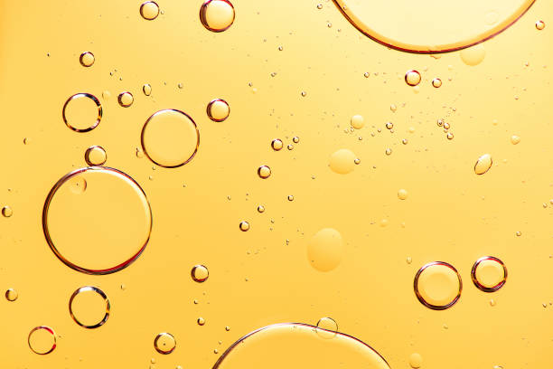 hermosa macro foto de gotas de agua en aceite con un fondo amarillo. - aceite para cocinar fotos fotografías e imágenes de stock