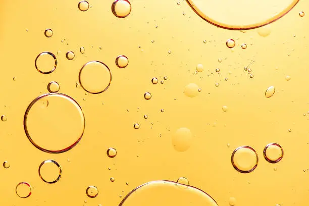Photo of Beautiful macro photo of water droplets in oil with a yellow background.