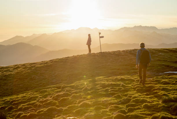 istock Couple walk up high grassy field, trail marker 1304045313