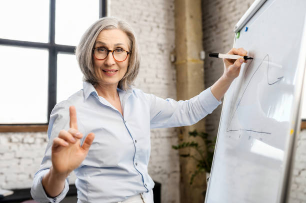 istock Mature female teacher writing on a whiteboard 1304046360