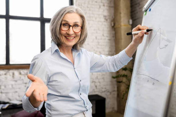 istock Mature female teacher writing on a whiteboard 1304046371