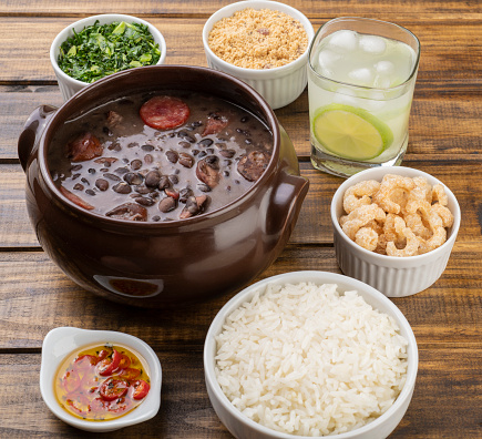 Traditional brazilian feijoada with kale, rice, cracklings, manioc flour and caipirinha.