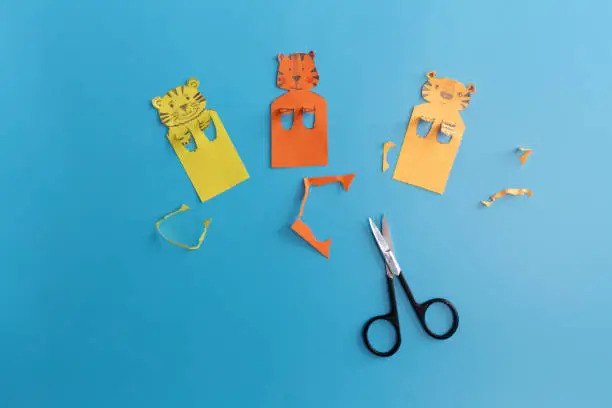 set of handmade bookmarks with tiger or cat on blue background, interesting paper craft for kids, step by step instruction, DIY, art project, step 2