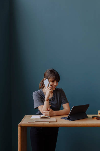 istock Women in Business: a Smiling Young Businesswoman Having a Phone Call while Using a Digital Tablet at her Office 1304049625