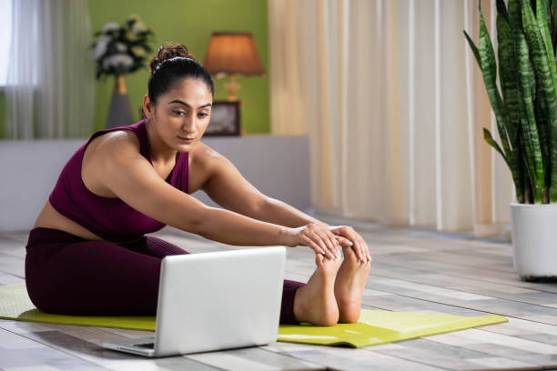 young woman doing yoga at home, stock photo young woman doing yoga at home touching toes stock pictures, royalty-free photos & images