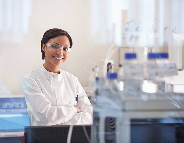 scienziato indossando occhiali protettivi in laboratorio - research smiling scientist women foto e immagini stock